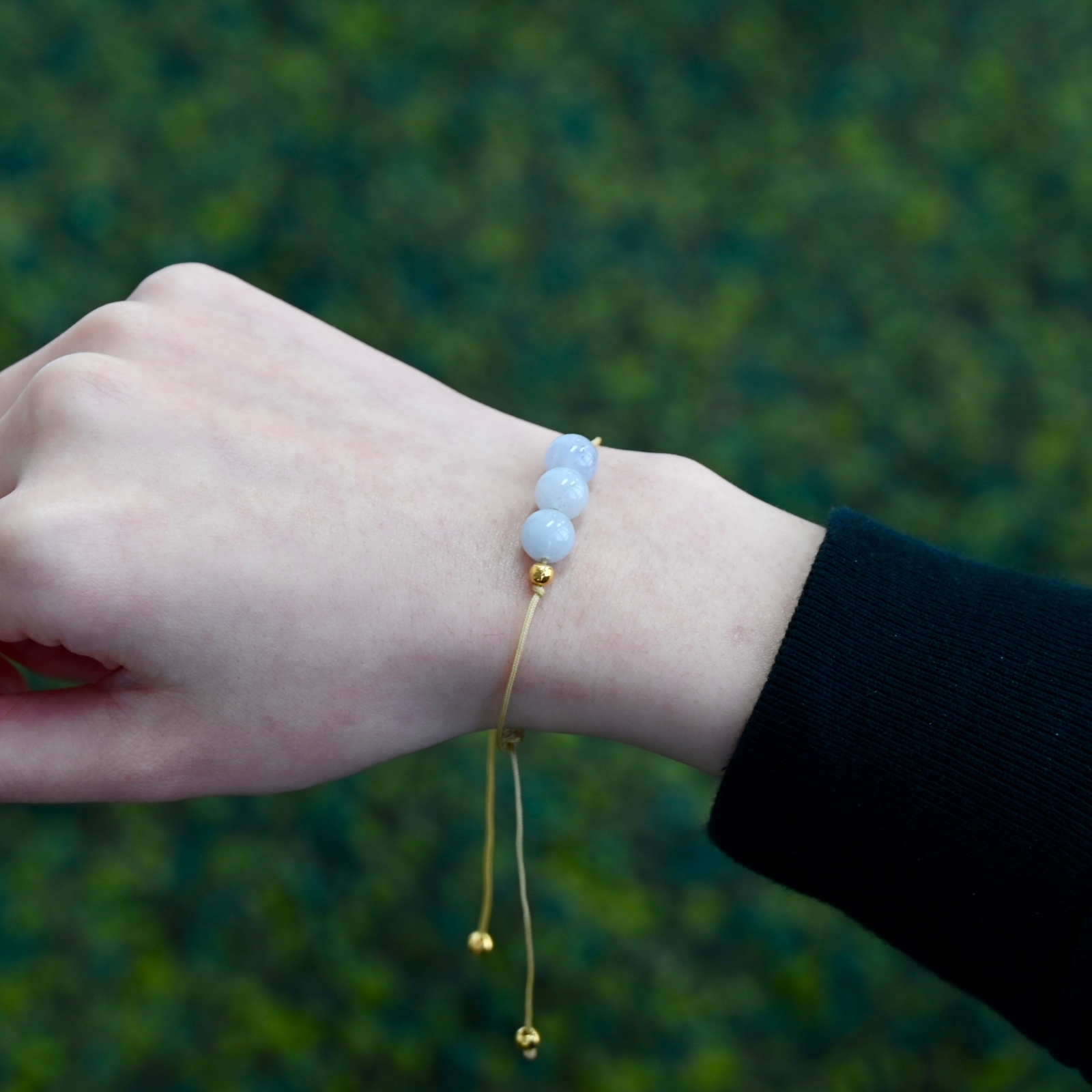 Asgard Glacier ID mist mineral bracelet worn on wrist with pale blue beads, gold-tone accents, and adjustable cord.